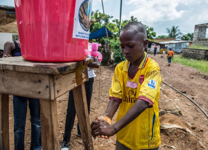 Santigi Tricket washes his hands at a Caritas stand. In Sierra Leone, CRS and its partner Caritas have been working to train more than 400 volunteers on key messages about Ebola as well as psychosocial counseling for those who've lost loved ones to the disease. Education is the only way to stop the spread of the disease, so CRS has been working on public awareness campaigns aimed at teaching the population about Ebola, including its spread and prevention. Photo by Tommy Trenchard for Caritas