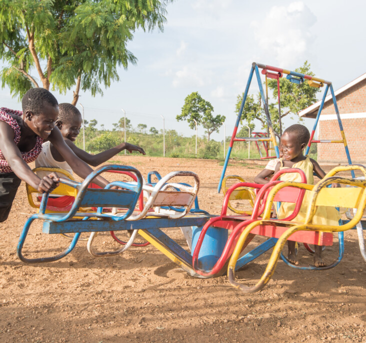 Annet Konga and her family enjoy a playground at the local child-friendly space. These spaces are part of CRS programming and provide a place where children who are dealing with trauma and interrupted educations can learn and heal through play. Photo by Philip Laubner/CRS.