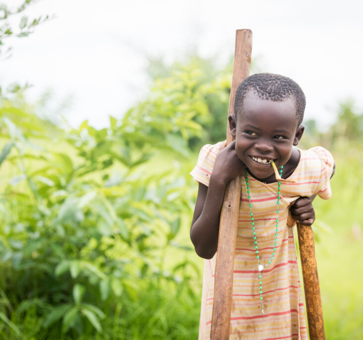 Irene, 8, wields a tool of her own to help Annet collect mud for their new shelter. Photo by Philip Laubner/CRS.