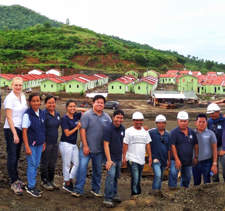 Anibong construction workers gather in front of the nearly complete development, which will house more than 900 families. Photo by CRS Staff.