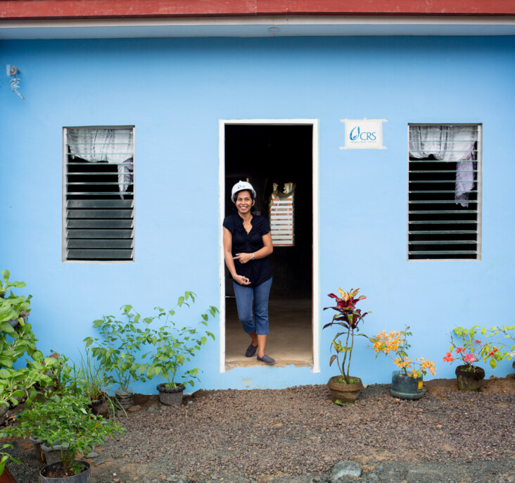 Girlita Ascalona, 37, stands proudly in front of her new home in the Anibong resettlement community. Her previous home was destroyed by Typhoon Haiyan in 2013. CRS is helping her to navigate the complicated process of home ownership. Photo by Jennifer Hardy/CRS.