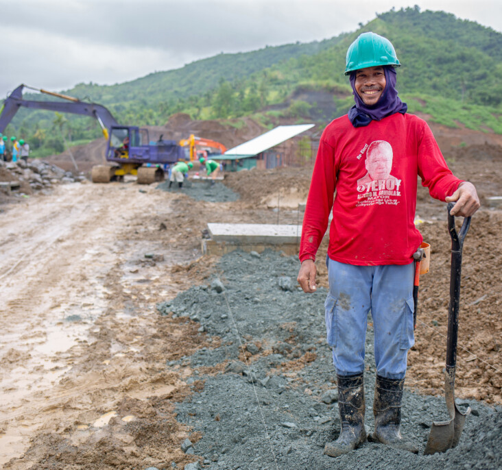 A construction worker stands in the Anibong resettlement site. He is one of many working to provide the new development critical infrastructure like roads and drainage. Photo by Jennifer Hardy/CRS.